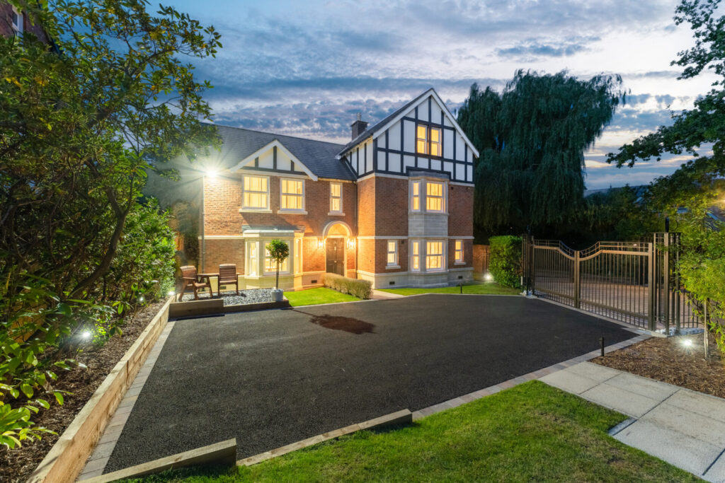 Detached mock Tudor home and driveway lit up at dusk at 1 Holland Park, Bramhall